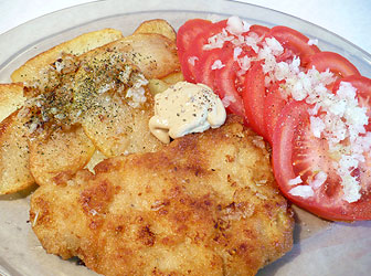 Polish schnitzel - kotlet schabowy with tomato and potatoes fried on oil
